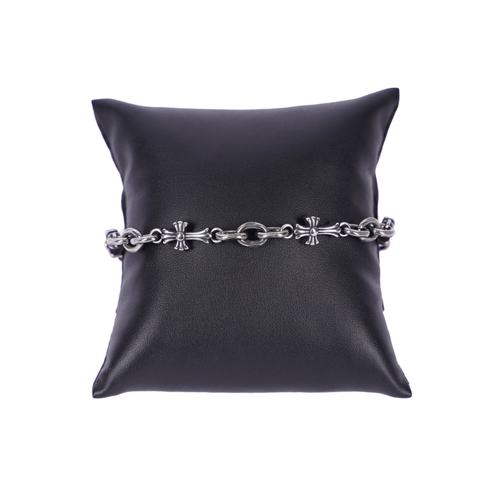 Silberfarbenes Mancino Gliederarmband aus Edelstahl mit kunstvoll integrierten Kreuz-Motiven, stilvoll präsentiert auf einem schwarzen Präsentationskissen vor weißem Hintergrund. Hochwertige italienische Handwerkskunst.