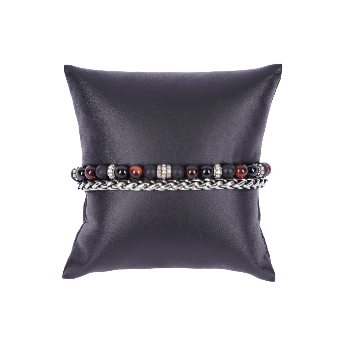 Zweilagiges Herrenarmband von Mancino aus einer silbernen Edelstahlkette und einer Perlenkette mit 6mm großen schwarzen und dunkelbraunen Natursteinen auf einem schwarzen Kissen.