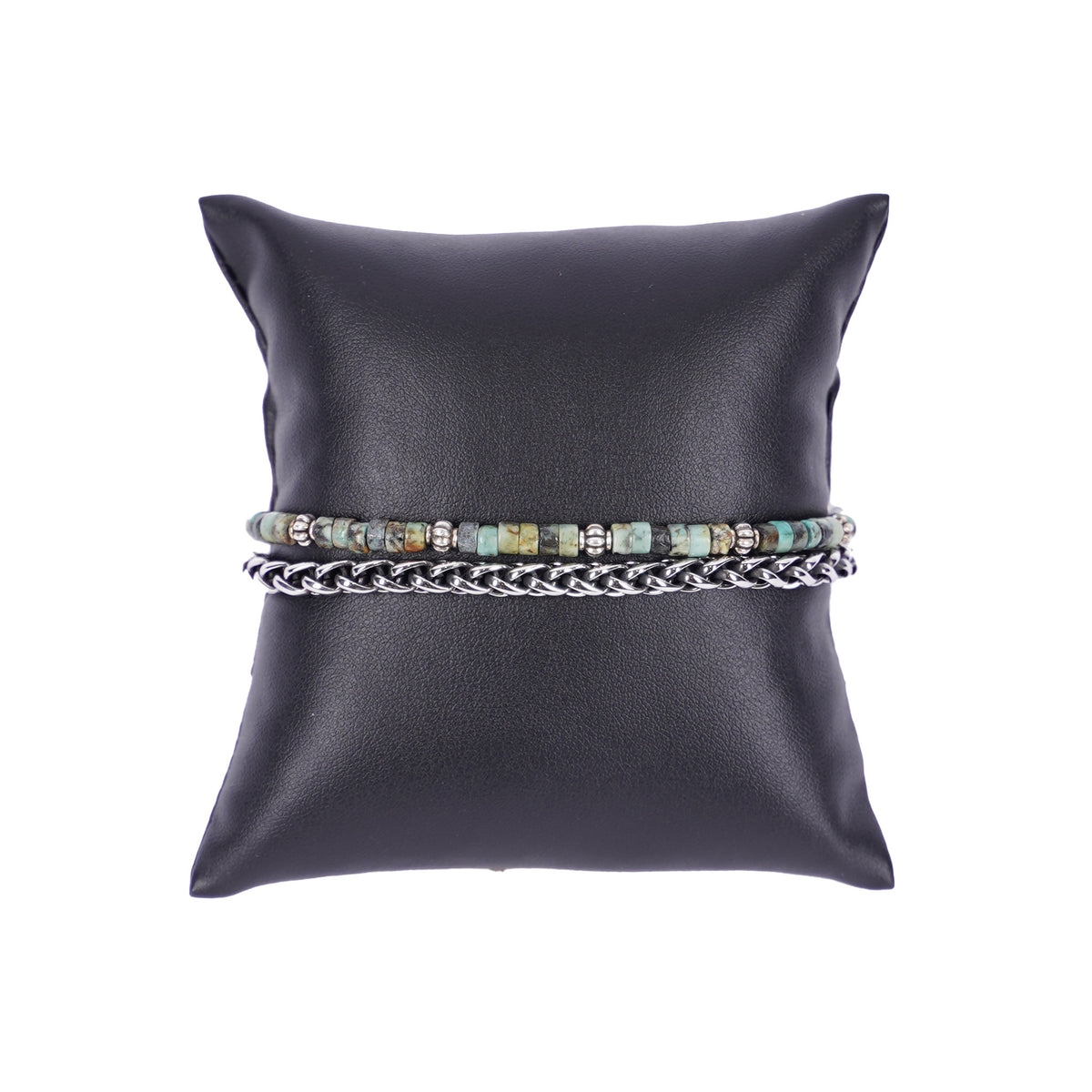 Zweilagiges Herrenarmband von Mancino aus einer silbernen Edelstahlkette und einer Perlenkette mit kleinen türkisfarbenen Stein-Rondelline auf einem schwarzen Kissen.