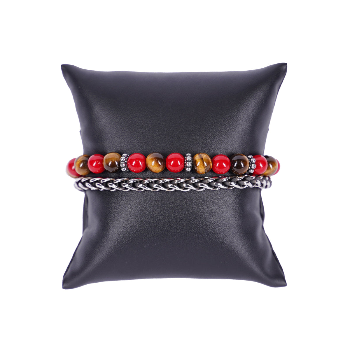 Zweireihiges Mancino Armband "Due Giri", elegant präsentiert auf einem schwarzen Kissen. Eine Reihe besteht aus einer geflochtenen Edelstahlkette, die zweite aus massiven 8mm Natursteinen im Wechsel von leuchtendem Rot und goldbraunem Tigerauge, getrennt durch antiksilberne Details.