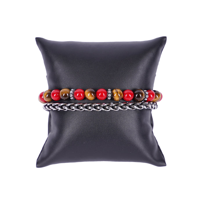 Zweireihiges Mancino Armband "Due Giri", elegant präsentiert auf einem schwarzen Kissen. Eine Reihe besteht aus einer geflochtenen Edelstahlkette, die zweite aus massiven 8mm Natursteinen im Wechsel von leuchtendem Rot und goldbraunem Tigerauge, getrennt durch antiksilberne Details.