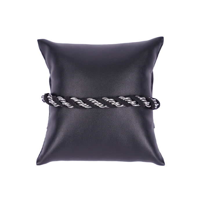 Schwarzes Mancino Armband aus echtem Leder mit kunstvoll eingewebten Elementen aus glänzendem Edelstahl, stilvoll präsentiert auf einem schwarzen Präsentationskissen vor weißem Hintergrund. Hochwertige italienische Handwerkskunst.