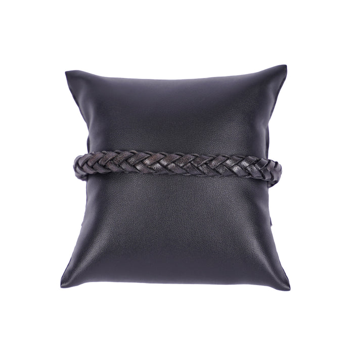 Dunkles, geflochtenes Mancino Lederarmband, elegant präsentiert auf einem schwarzen Präsentationskissen vor weißem Hintergrund. Hochwertige italienische Handwerkskunst.