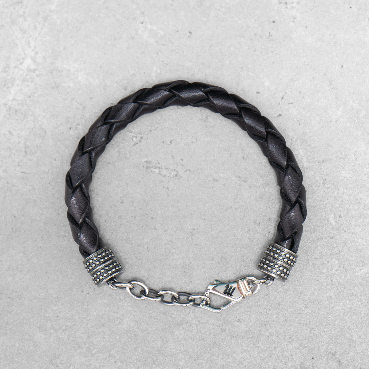 Schwarzes, geflochtenes Mancino Lederarmband Treccia Pelle für Herren bei Ricci Uomo. Markantes Design mit glänzenden Edelstahl-Endkappen und Karabinerverschluss.