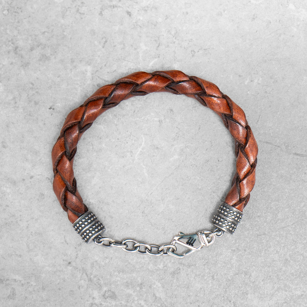 Dunkelbraunes, geflochtenes Mancino Lederarmband Treccia Pelle für Herren bei Ricci Uomo. Markantes Design mit glänzenden Edelstahl-Endkappen und Karabinerverschluss.