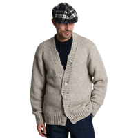 Lässiger Heritage-Look mit dem beigen Xagon Cardigan. Das Model kombiniert die grob gestrickte Jacke mit den gewollten Rissen (Rotture) stilvoll mit einer karierten Schiebermütze.