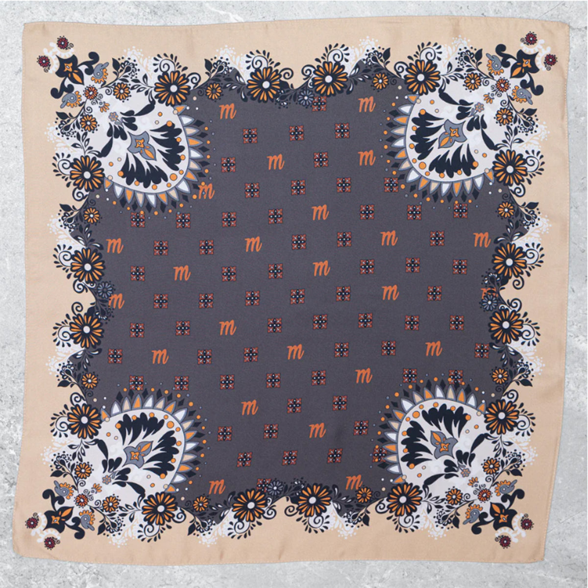 Flach ausgebreitetes Mancino Seiden-Foulard (100% Seide). Das Design zeigt ein dunkelgraues Zentrum mit orangefarbenen 'm'-Logos und eine aufwendige florale Paisley-Bordüre in Sand, und Orange.