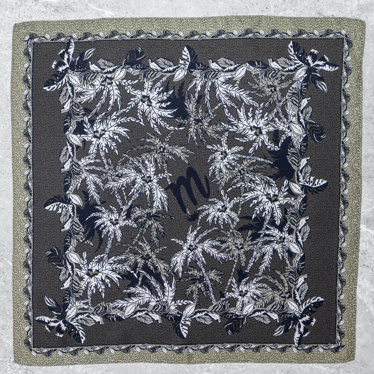 Flach ausgebreitetes Mancino Seiden-Foulard aus 100% Seide. Das Design zeigt ein schwarzes 'm'-Logo im Zentrum, umgeben von detaillierten schwarz-weißen Palmenblättern auf khakigrünem Grund mit gemusterter Bordüre.