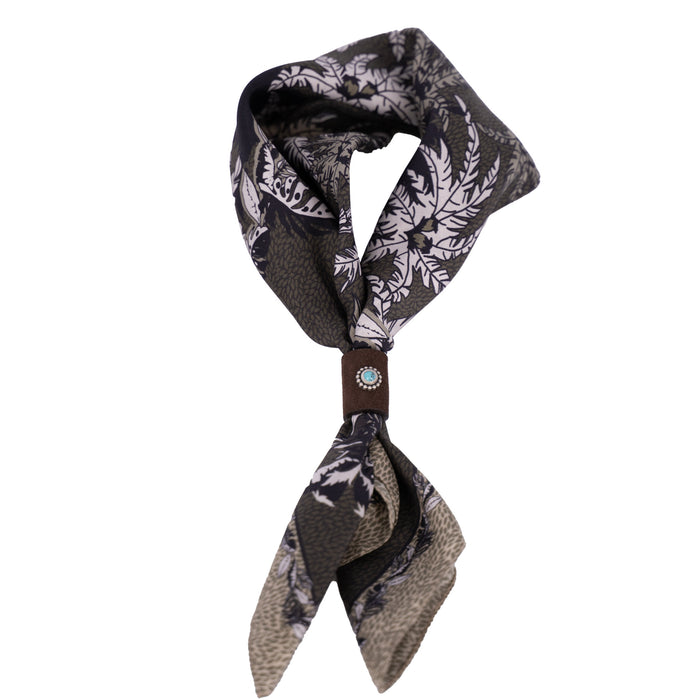 Geknotetes Mancino Seiden-Foulard "Tropical Green" (51x51 cm) mit Palmenmuster, fixiert durch ein braunes Leder-Bolo mit türkisfarbenem Naturstein, freigestellt auf weißem Hintergrund.