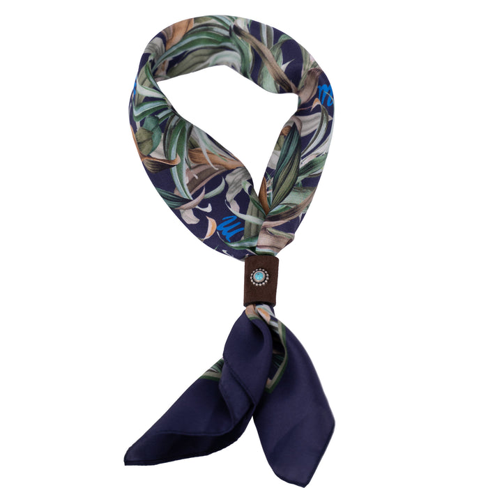 Geknotetes Mancino Seiden-Foulard "Tropical Navy" (51x51 cm) mit exotischem Blättermuster in Grün und Braun auf dunkelblauem Grund und hellblauen 'm'-Logos. Fixiert durch ein braunes Leder-Bolo mit türkisfarbenem Naturstein, freigestellt auf weißem Hintergrund.