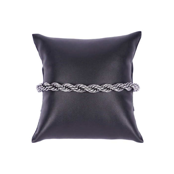 Silberfarbenes Mancino Armband aus massivem Edelstahl im kunstvoll geflochtenen Kordel-Design, elegant präsentiert auf einem schwarzen Präsentationskissen vor weißem Hintergrund. Hochwertige italienische Handwerkskunst.