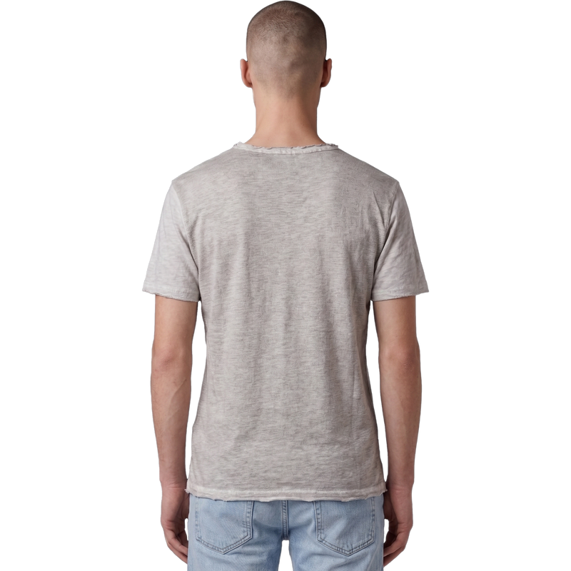 Rückansicht eines männlichen Models in dem beigefarbenen T-Shirt. Der Fokus liegt auf der feinen Melange-Struktur des Stoffes, dem lässigen Schnitt und dem leicht ausgefransten Raw-Edge-Saum am unteren Bund. Das Model trägt eine hellblaue Jeans.