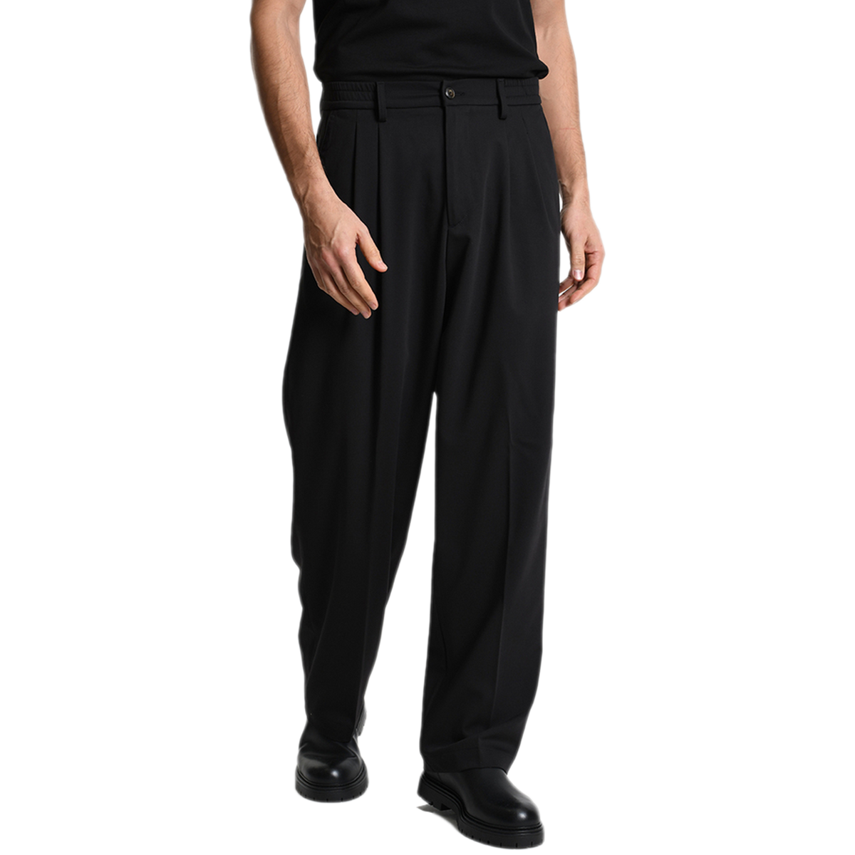 Vorderansicht der schwarzen Xagon Wide Fit Hose bei Ricci Uomo. Das Model trägt die weit geschnittene Hose mit doppelten Bundfalten, die für eine elegante, fließende Silhouette sorgen.